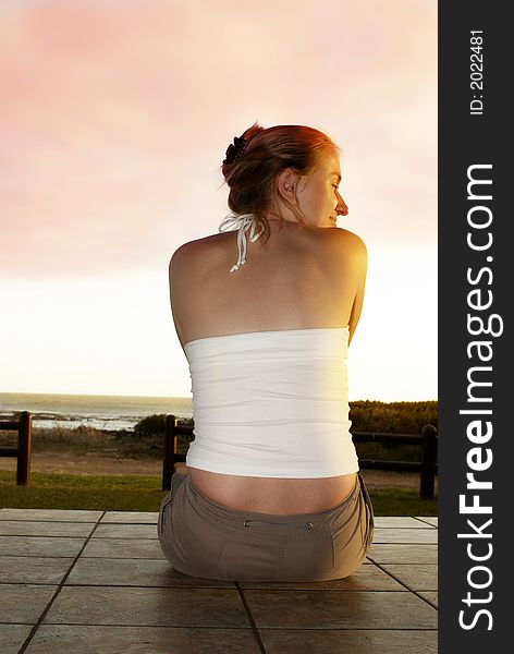 Beautiful woman sitting on the tiled porch outside, by the ocean in South Africa. Beautiful woman sitting on the tiled porch outside, by the ocean in South Africa.