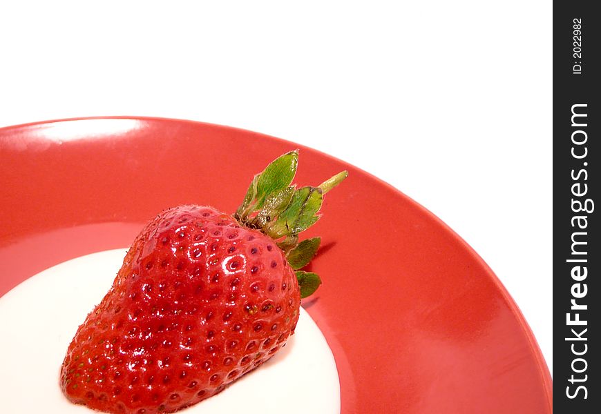 One fresh strawberry with cream on red plate. One fresh strawberry with cream on red plate