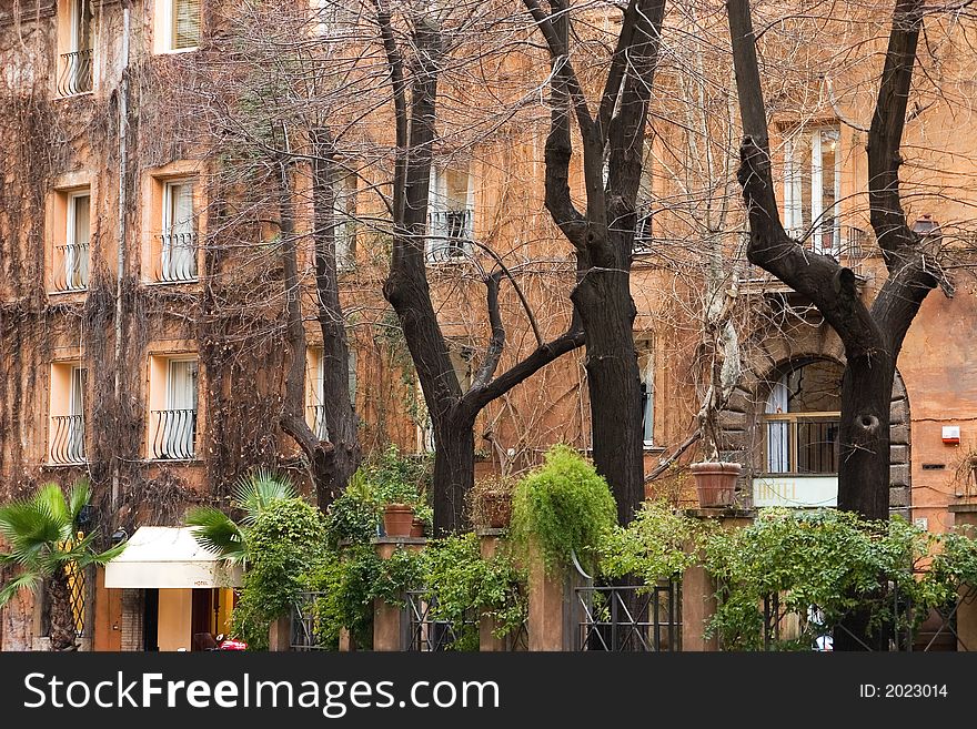 Hotel front in Rome, Italy in spring with leafless trees in the front.