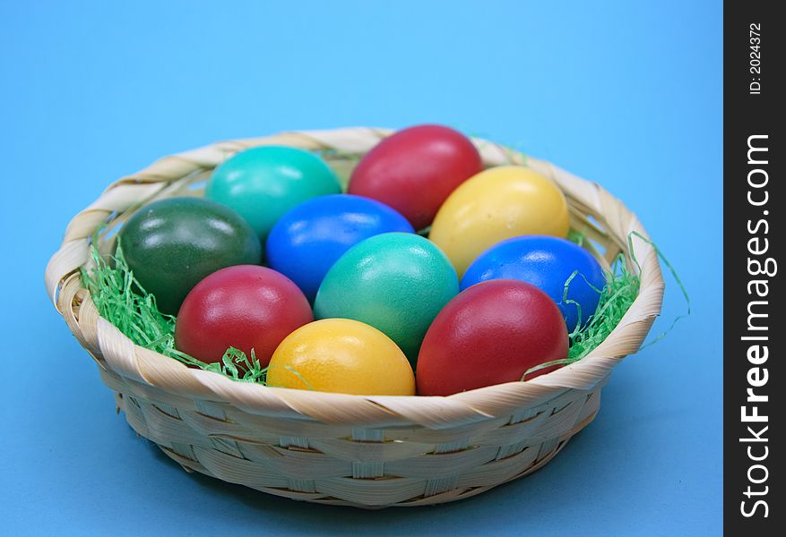 Colored eggs in basket on  blue background