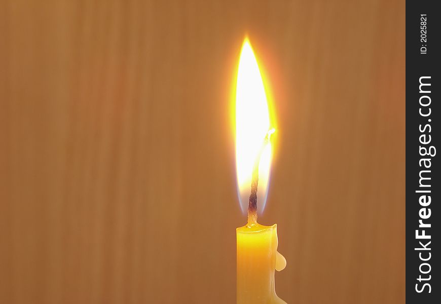 Burning candle at the brown background . Burning candle at the brown background