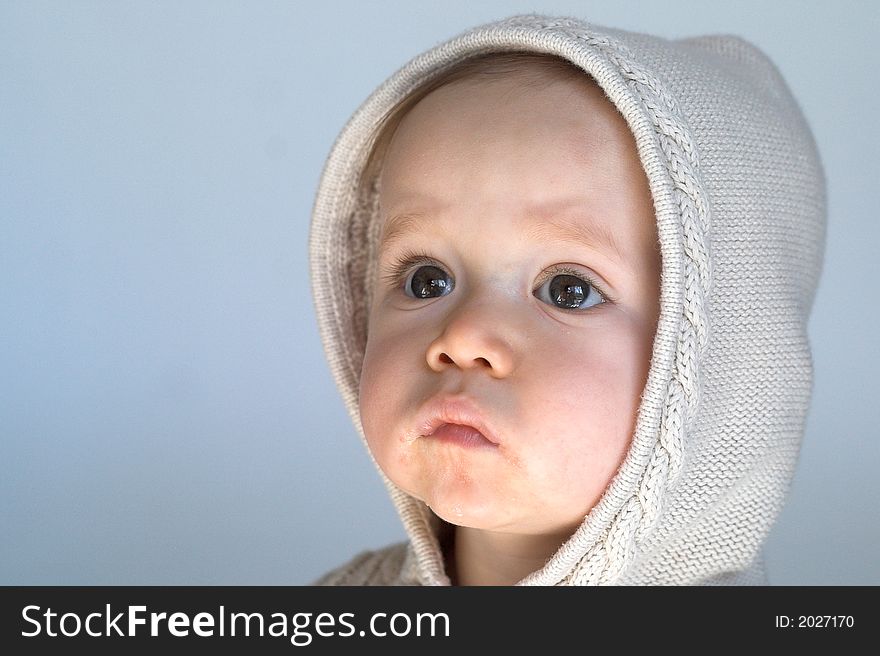 Image of cute baby wearing a hooded sweater, sitting in front of a white background. Image of cute baby wearing a hooded sweater, sitting in front of a white background