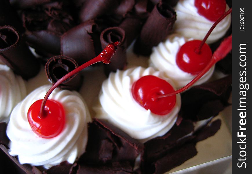 Icing of dark chocolate cake with maraschino cherry topping. Icing of dark chocolate cake with maraschino cherry topping