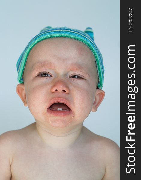 Image of crying baby sitting in front of a white background