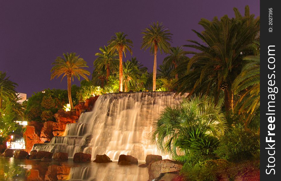 This is a waterfall surrounded by palm trees and a little lake