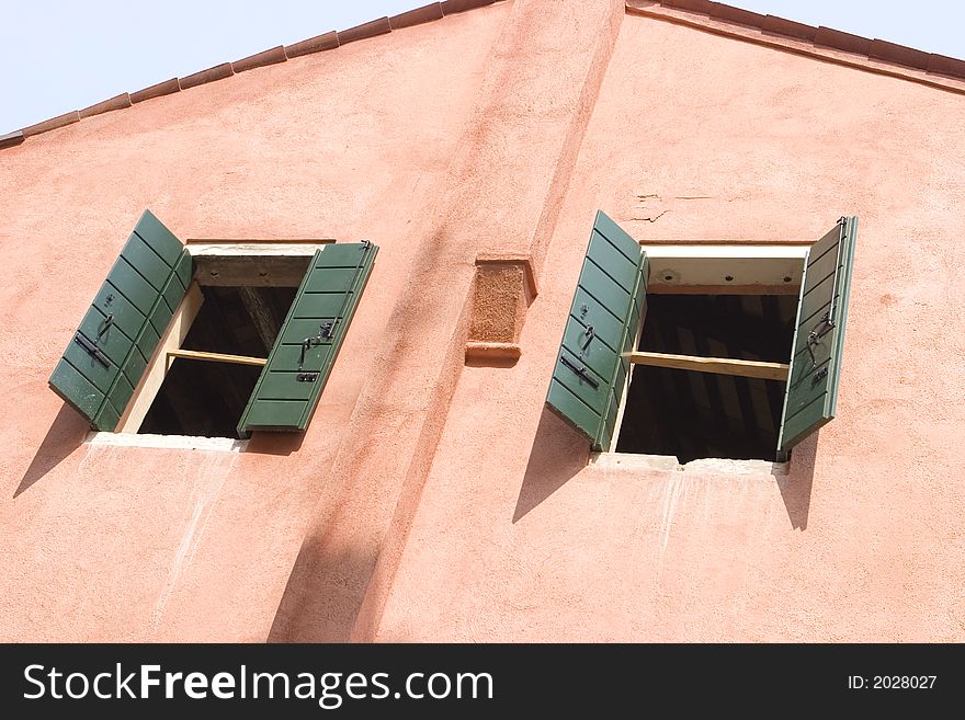 A house with open green shutters and a light blue sky