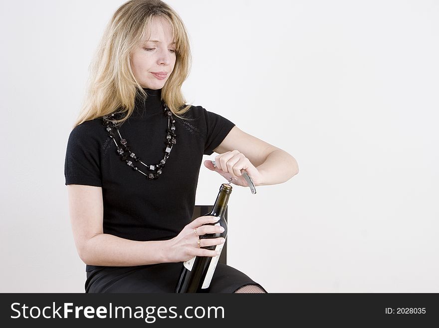 A woman opening a bottle of red wine. A woman opening a bottle of red wine