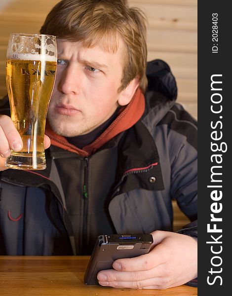 Man looking at beaker of beer and holding palm-size computer.