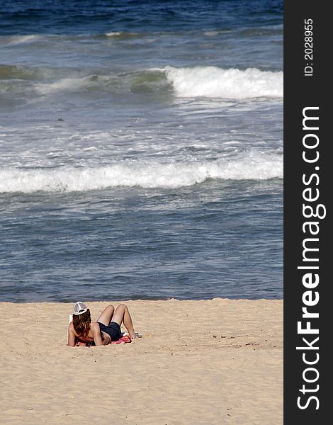 Girl At A Sandy Beach Reading A Book And Looking At The Ocean Waves. Girl At A Sandy Beach Reading A Book And Looking At The Ocean Waves