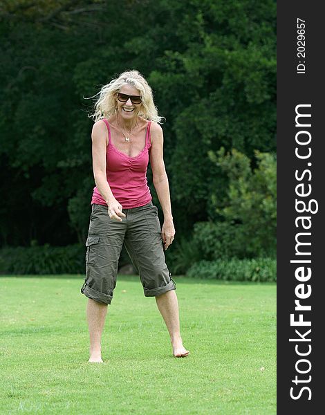 Healthy woman in her fifties laughing, standing on grass. See my other happy person jumping shots in my portfolio!. Healthy woman in her fifties laughing, standing on grass. See my other happy person jumping shots in my portfolio!