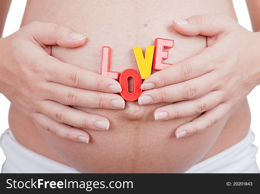 Pregnant woman hold word love on a belly on grey background