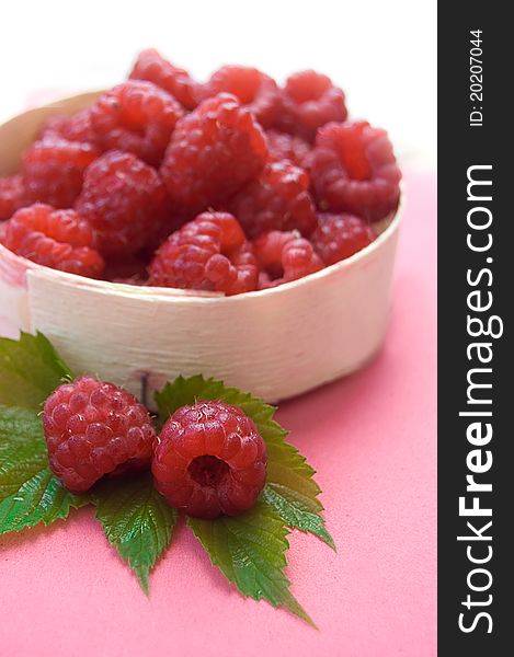 Raspberries in wooden basket with leaves