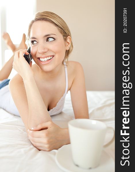 Beautiful white women having a happy conversation looking right on bed with coffee cup. Beautiful white women having a happy conversation looking right on bed with coffee cup