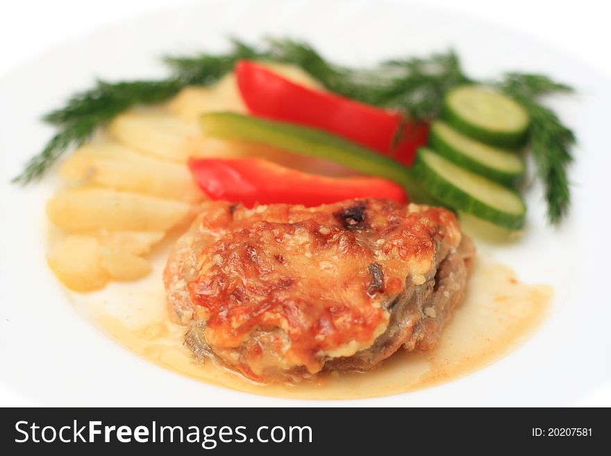 Piece of meat with vegetables on a white plate