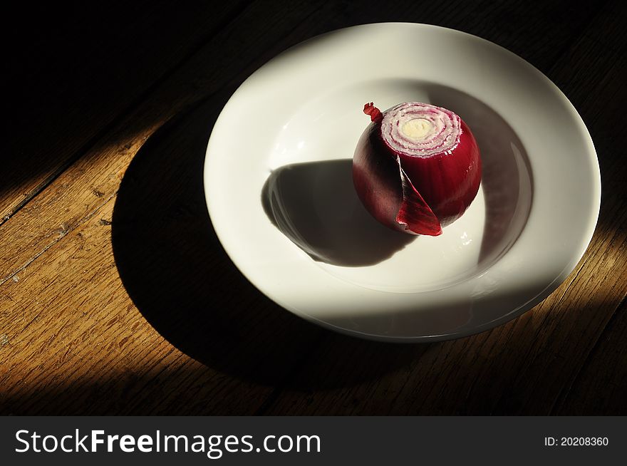 Red onion on a Limoges porcelain plate with shadows. Red onion on a Limoges porcelain plate with shadows