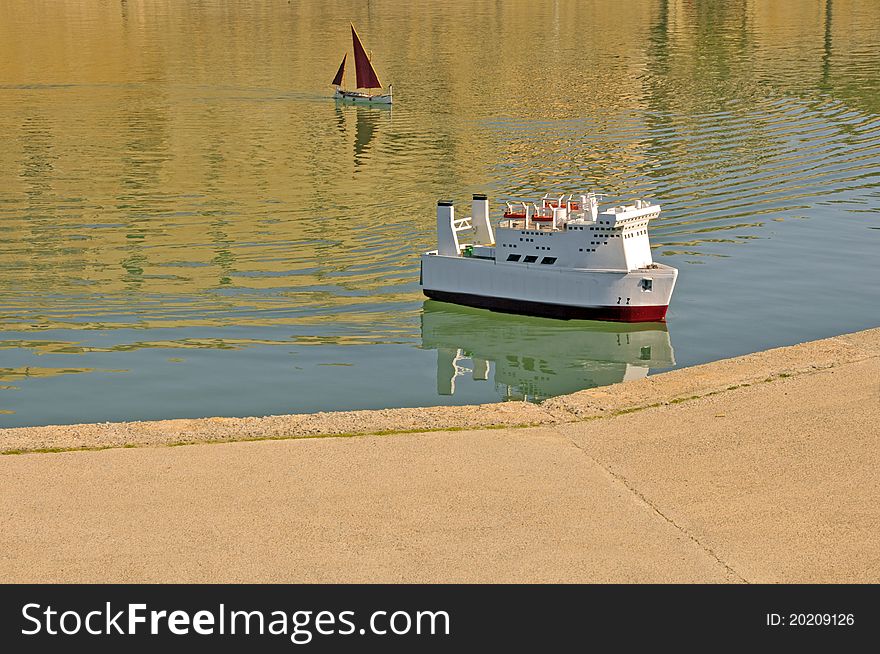 Sailing two toy boats on water with reflection