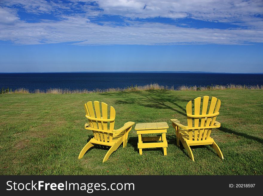 Two yellow Adirondack Chairs sitting on the garden facing the ocean. Two yellow Adirondack Chairs sitting on the garden facing the ocean