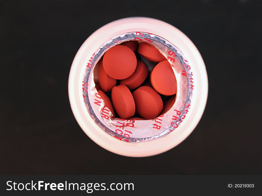 Small bottle of pills over black background