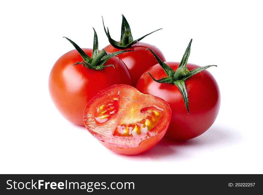 Red ripe tomatoes, two whole and one halved. Red ripe tomatoes, two whole and one halved