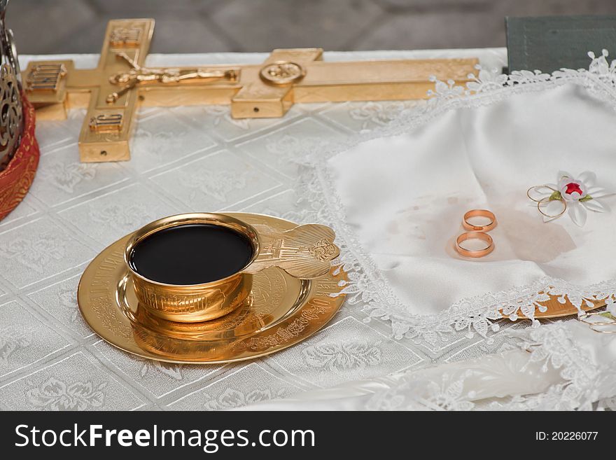 Wedding rings lay on a table near a bowl with wine. Wedding rings lay on a table near a bowl with wine