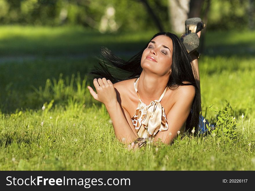 Young beautiful brunette lying on the grass on a summer day