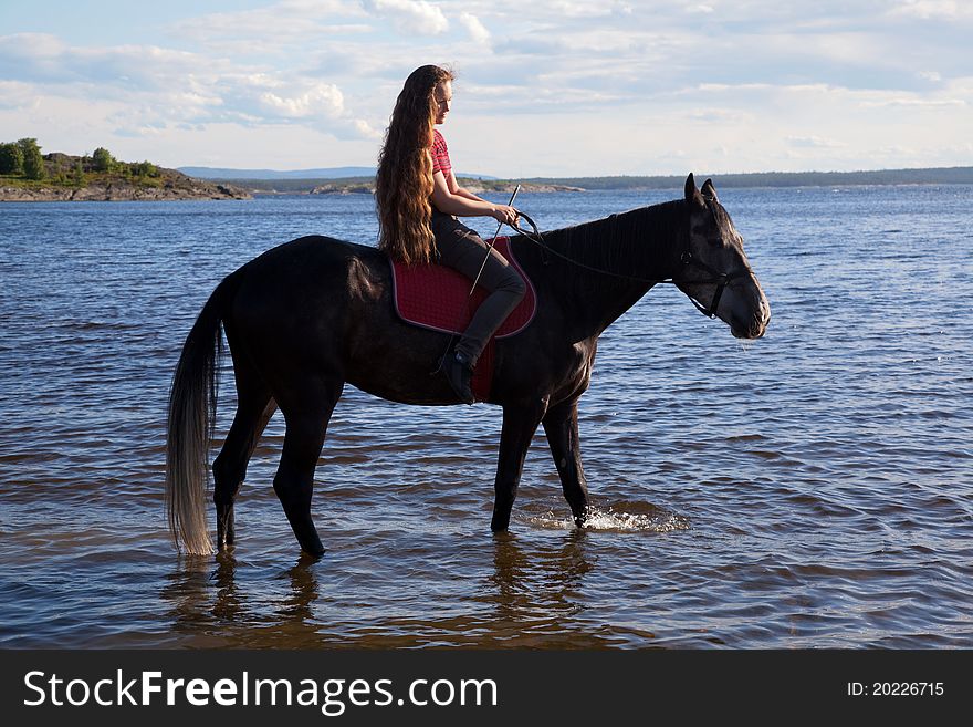 The girl has a horse to water in the evening at sunset. The girl has a horse to water in the evening at sunset