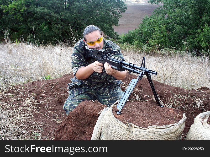 An airsoft player with an M60 machinegun during an outdoor game. An airsoft player with an M60 machinegun during an outdoor game.