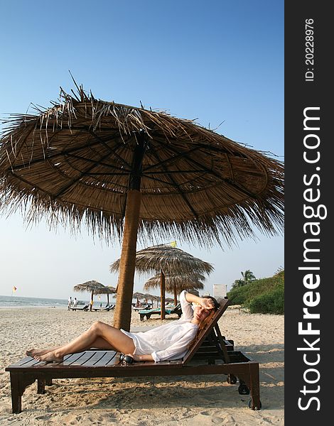 Woman on the beach under umbrella from palm. Woman on the beach under umbrella from palm