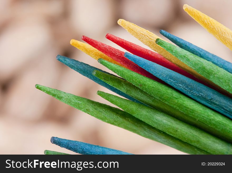 Wooden multi-coloured toothpicks for personal hygiene. Nuts as a background.