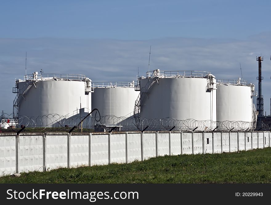 Several fuel-tank behind a fence topped with barbed wire. Several fuel-tank behind a fence topped with barbed wire