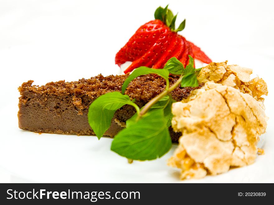 Close-up of slice of chocolate cake decorated with mint and strawberry on white background. Close-up of slice of chocolate cake decorated with mint and strawberry on white background