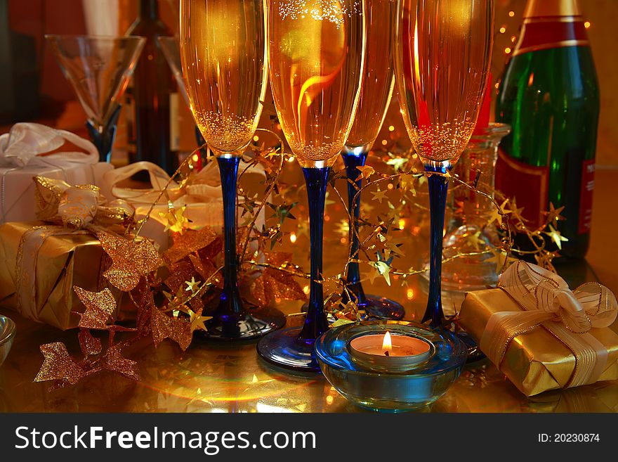 Close-up of champagne in glasses,gift box,candlelights and lights on golden background.