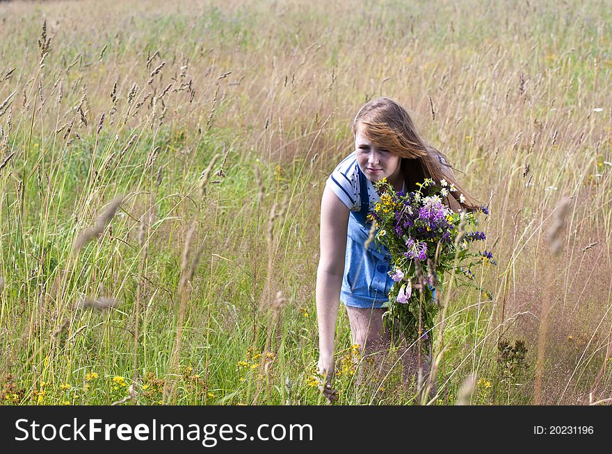 The red girl in the field collects a bunch of flowers