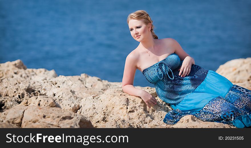 Pretty woman lying on the rocky mountain near the sea