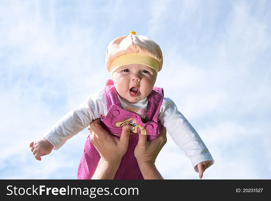 Father playing with baby, raised it high above them, against the background of blue sky. Father playing with baby, raised it high above them, against the background of blue sky