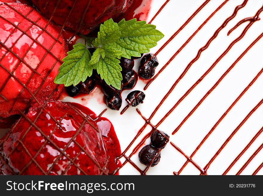 Berry fruit ice cream served on the white plate. Decorated with mint.