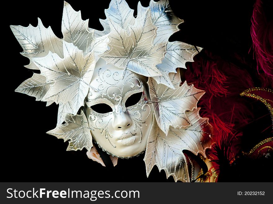 A white venetian carnaval mask with leaves as ornaments. A white venetian carnaval mask with leaves as ornaments