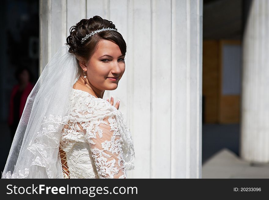 Happy bride near white columns outdoor