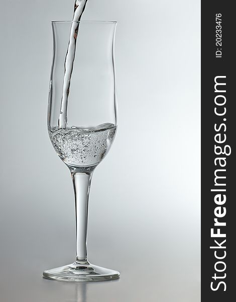 Pouring sparkling water in champagne glass isolated in white background. Pouring sparkling water in champagne glass isolated in white background