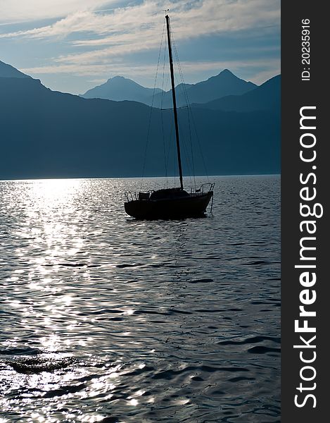 The image depicts the silhouette of a sailboat that was anchored until the next day. The image depicts the silhouette of a sailboat that was anchored until the next day.