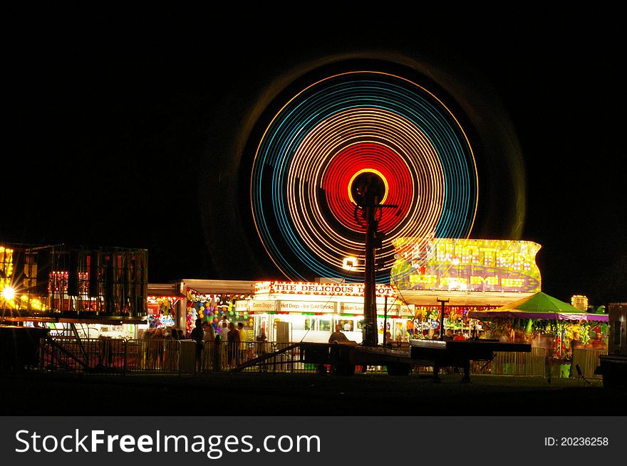 Along exposure of a carnival at night creates a hypnotic wheel of colors over the arcade. Along exposure of a carnival at night creates a hypnotic wheel of colors over the arcade.