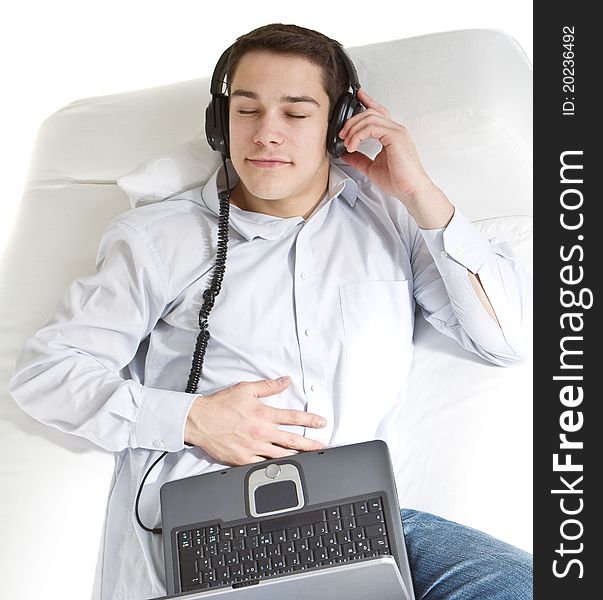 Young man relaxing on the couch listening to music over white background. Young man relaxing on the couch listening to music over white background.