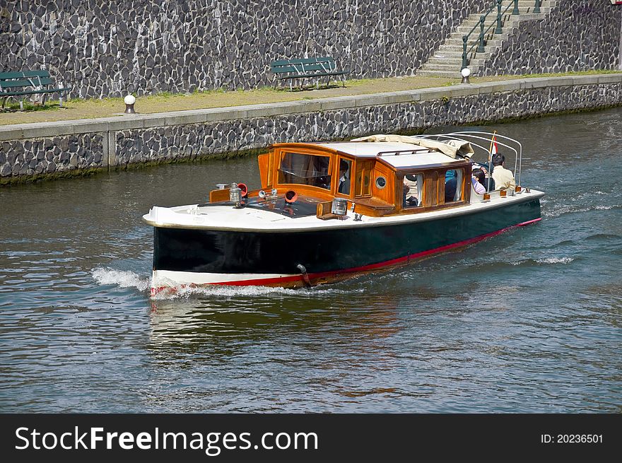 Passenger boat sails on the water channel along the stone quay.