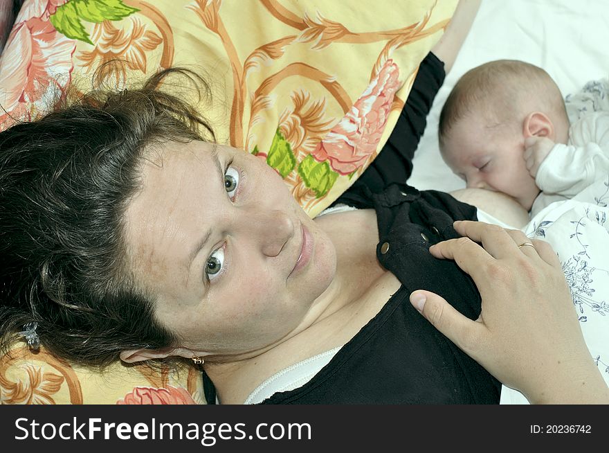 Mother feeding her baby laying in the bed. Mother feeding her baby laying in the bed