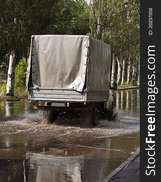 Small truck driving in the city after heavy rain