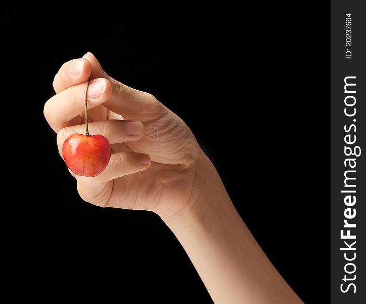 It is red a yellow sweet cherry lies on a hand of the young girl. It is red a yellow sweet cherry lies on a hand of the young girl