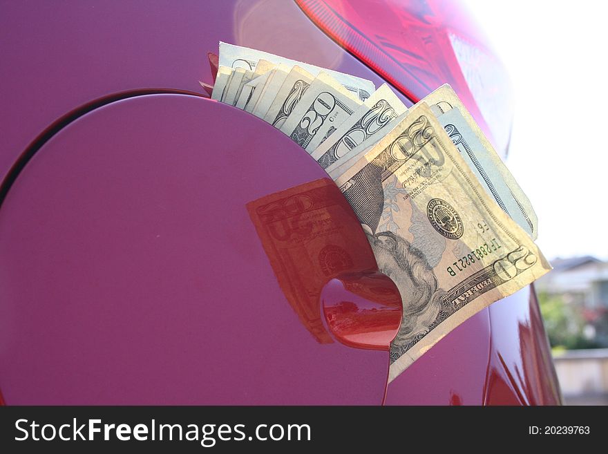 Money coming out of a gas tank in a red car. Money coming out of a gas tank in a red car.