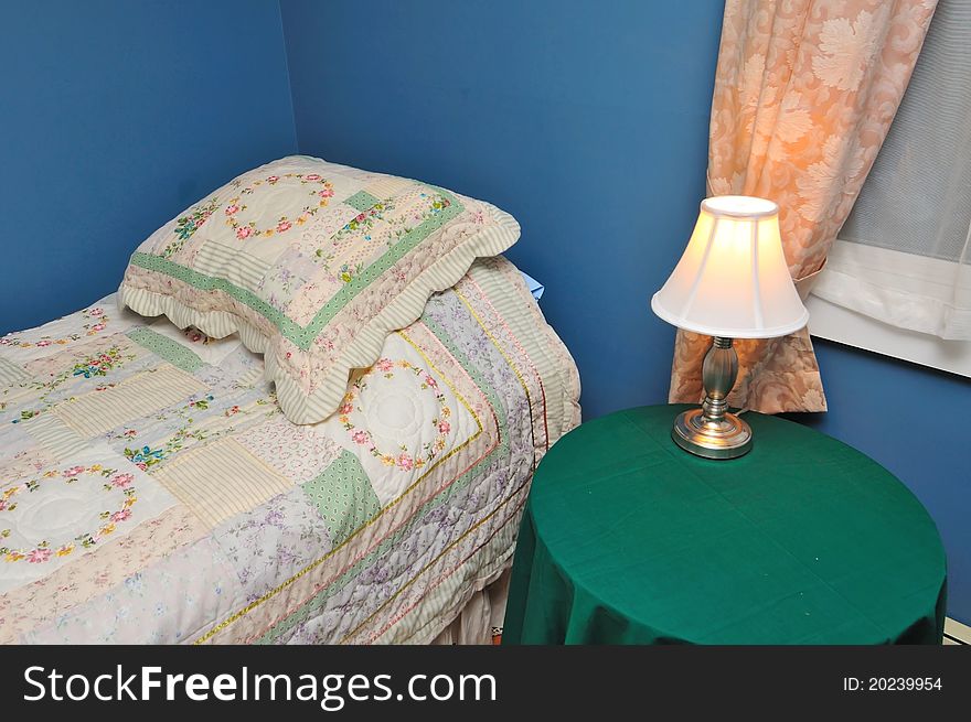 Side table with lighted lamp beside hotel bed. Side table with lighted lamp beside hotel bed.