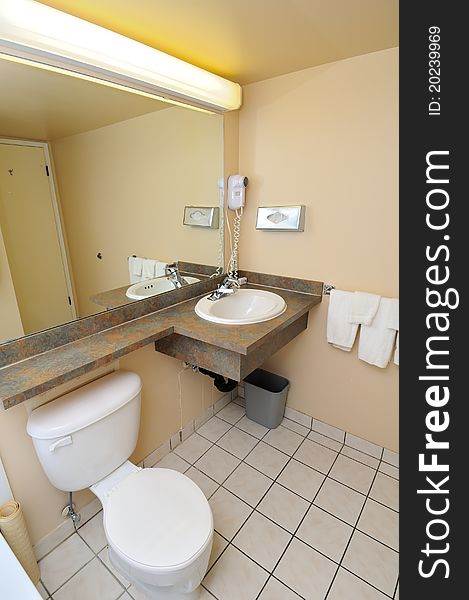 Typical hotel toilet area with toilet bowl, mirror and basin.