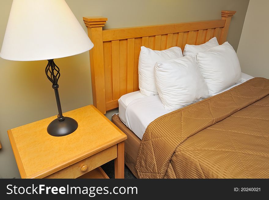 Clean and cozy bed with lamp on side table.